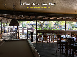 The patio and outdoor bar wraps around the building covered with oak trees for a relaxing dining experience at The Three Birds Tavern in St. Petersburg, Florida.