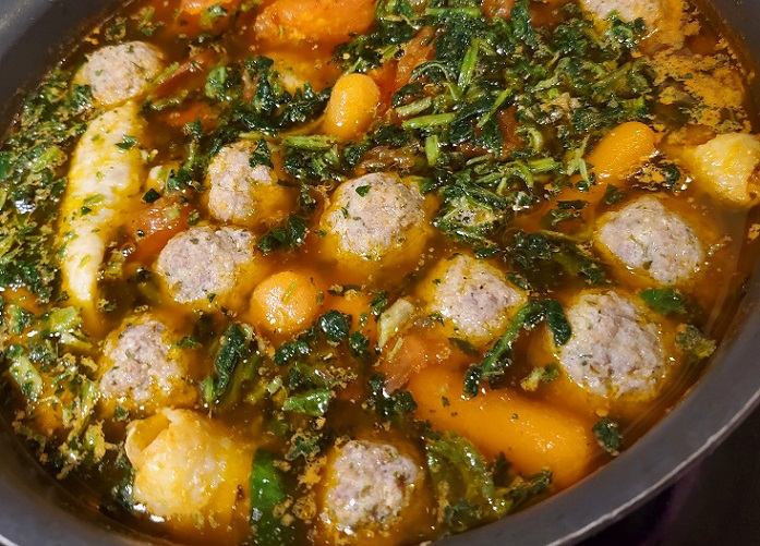 this is a pan of chicken soup spinach and meatballs