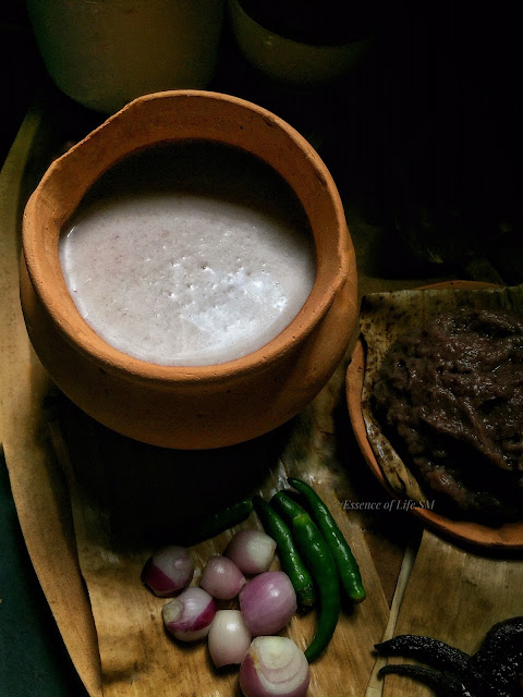 Close-up of Ragi Koozh in a clay pot, paired with green chillies, shallots, and ragi kali on banana leaf.