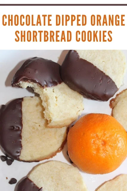 Finished chocolate-dipped orange shortbread cookies with a bite out of one cookie.