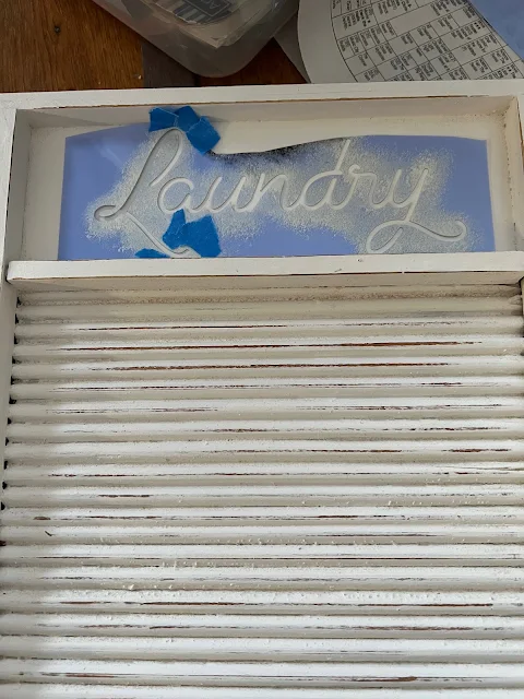 Photo of a scrap of a laundry stencil placed on a washboard shelf.