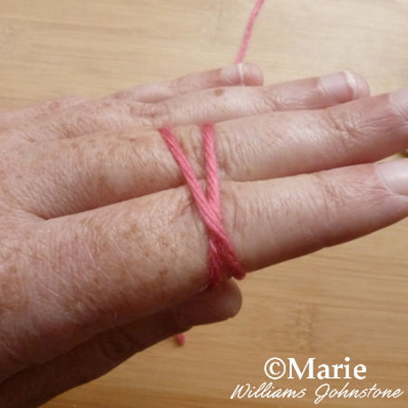 Crossed yarn wool strands over hand to make slip knot for crochet