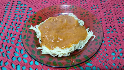 Sob a mesa, prato de espaguete com molho de tomates assados