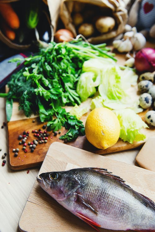Vegetables and fish lying on a chopping board indicating weight loss