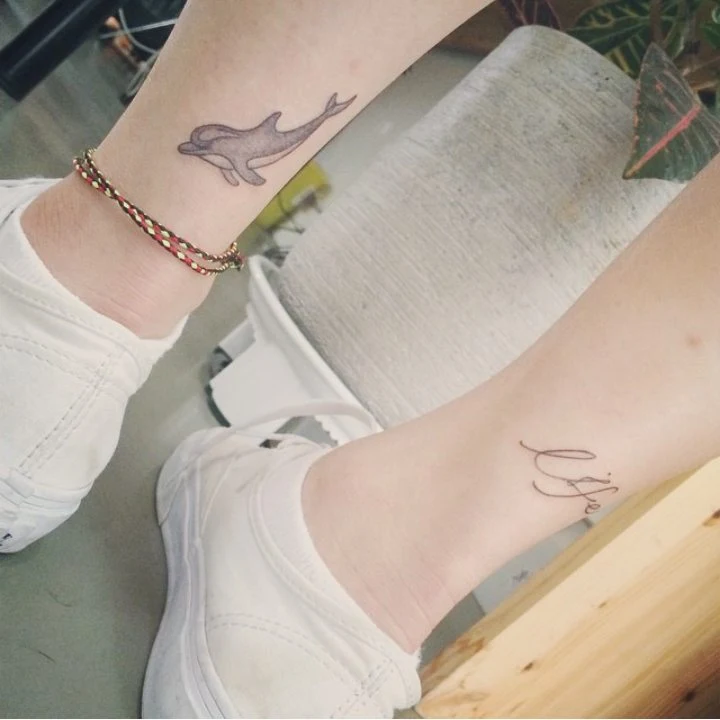 Una joven lleva tatuaje de delfín en el tobillo