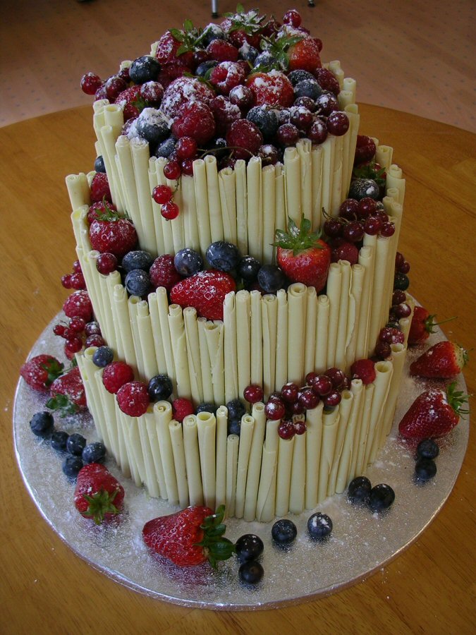 Three tier white chocolate cigarillo wedding cake with strawberries and blue