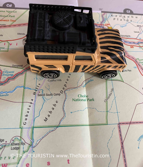 A beige and black painted toy Land Rover on a paper map next to the words Chobe National Park.