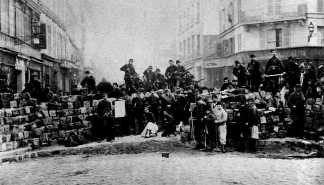 foto de barricada com pessoas armadas em cima e na frente da barricada    