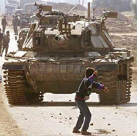 A Palestinian boy wields a stone against an Israeli tank