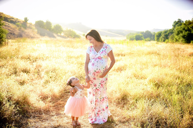 maternity shoot of mommy and daughter looking at each other