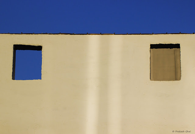 A Lookup Minimal Art Photograph of Two Windows on a Wall, one of which is open and the other one is closed. 