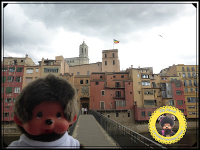 Bubbles le Monchhichi pose devant les façades colorées bordant le fleuve Onyar