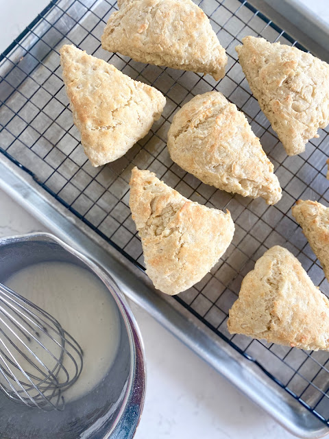 Spiced Apple Scones on a wire rack next to a bowl of icing.