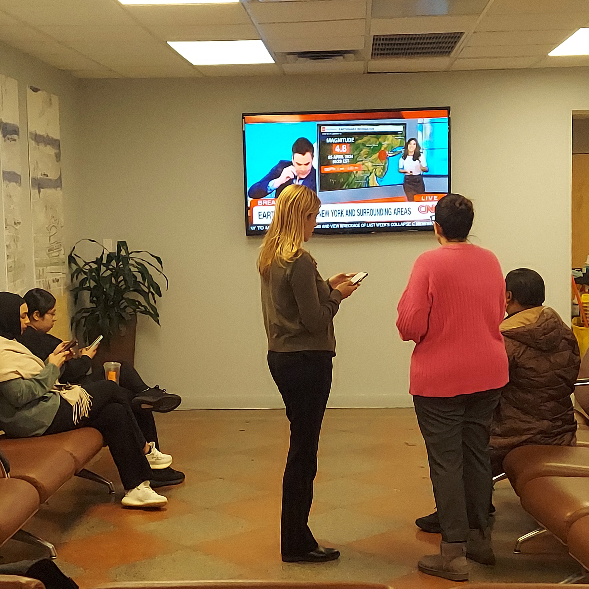 Students and faculty at Monroe College hover around a television as they learn of a reported 4.8 magnitude earthquake centered in New Jersey on Friday, April 5, 2024. -Photo by David Greene
