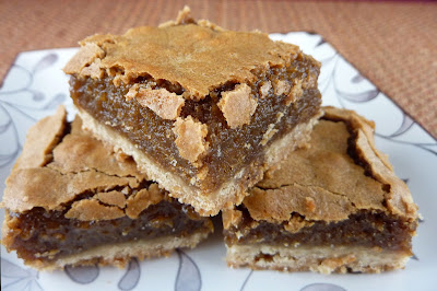 Three Brown Sugar Biscoff Bars, a bottom crust topped with a brown sugar/Biscoff topping. Photographed on a white patterned plate