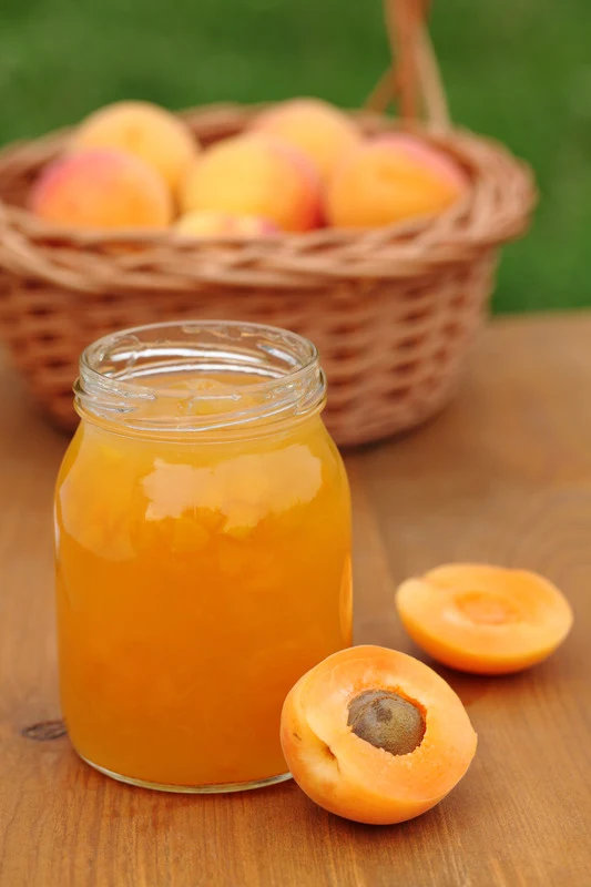 Glass with apricot jam and fresh apricots in basket