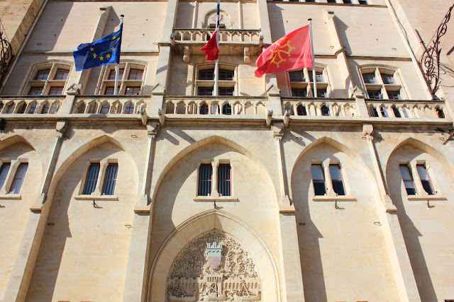 neogotycka fasada ratusza w Narbonie ozdobiona flagami 