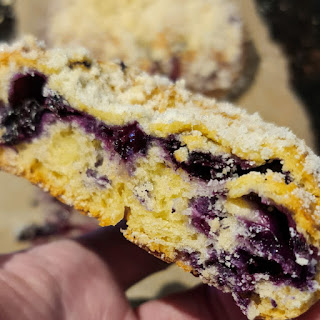 A cut half of a jagodzianka showing the bun texture and the blueberry filling