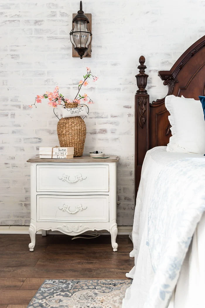 whitewashed brick wall, nightstand with woven vase and Spring blooms