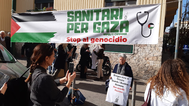 Altra foto della manifestazione succitata. Sullo sfondo uno striscione con una bandiera palestinese e la scritta "stop genocidio".