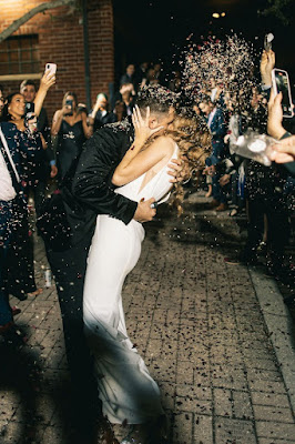 bride and groom kissing with confetti in the air