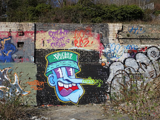 A photo of a large cartoon graffiti face painted on the wall around the site of the paper mill.  Photo by Kevin Nosferatu for the Skulferatu Project.