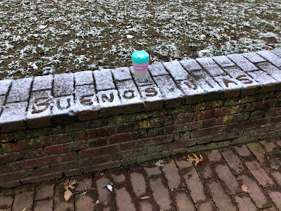 A brick wall with a dusting of snow, in which the message "Buenos Dias" has been traced out.