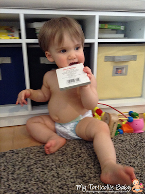 Baby with right torticollis chewing on a book.