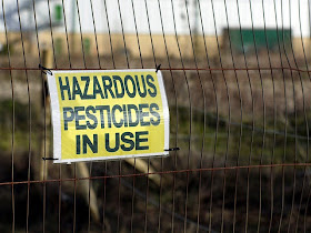 Photo of sign which says hazardous pesticides in use