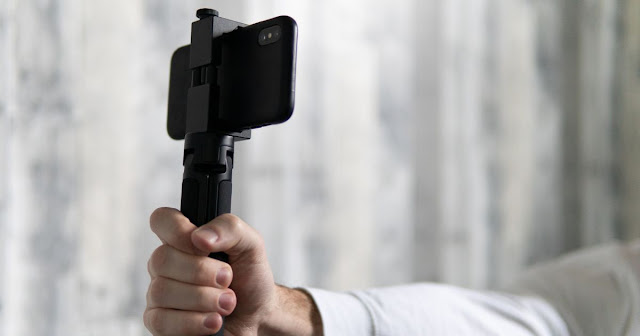 this is a picture of someone using a selfie stick showing how it is a must have mobile phone accessory in 2023