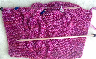 A pink scarf in bulky weight yarn.  It has one centre cable on a background of garter stitch.