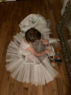 Little girl in a tutu sitting on the ground in front of a mirror