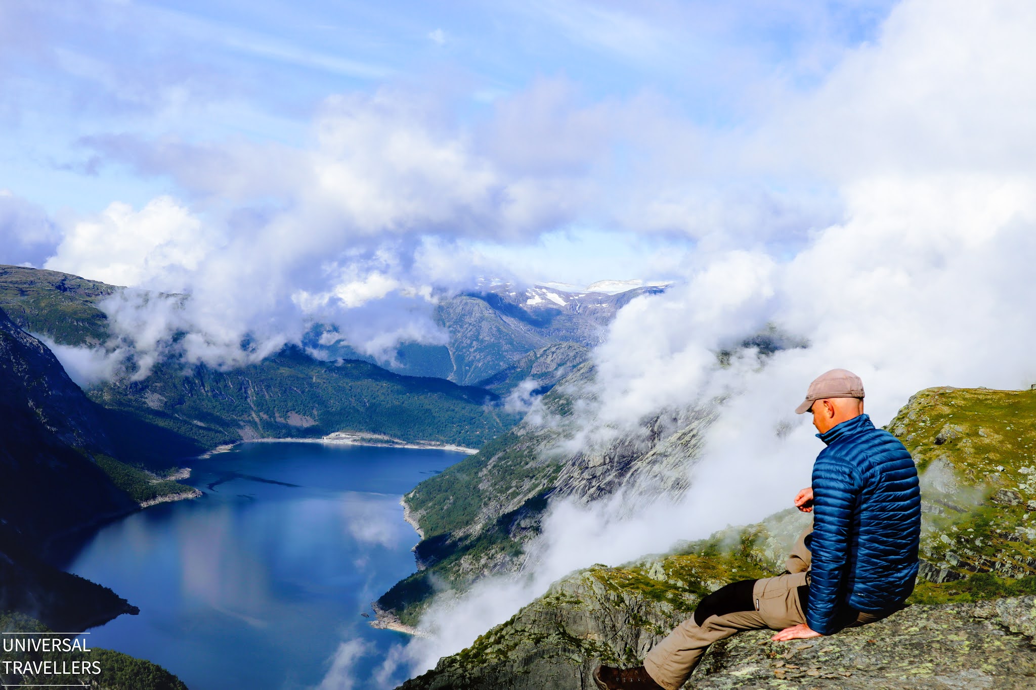 A hiker is sitting beside the Trolltunga cliff and enjoying the view of Lake Ringedalsvatnet