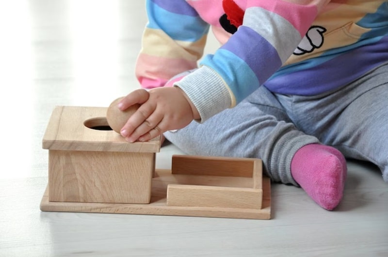 Baby playing with object permanence box.