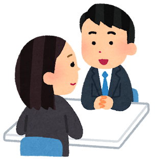 スーツを着た男女の同僚二人が机に肘をかけて楽しそうに会話しています
