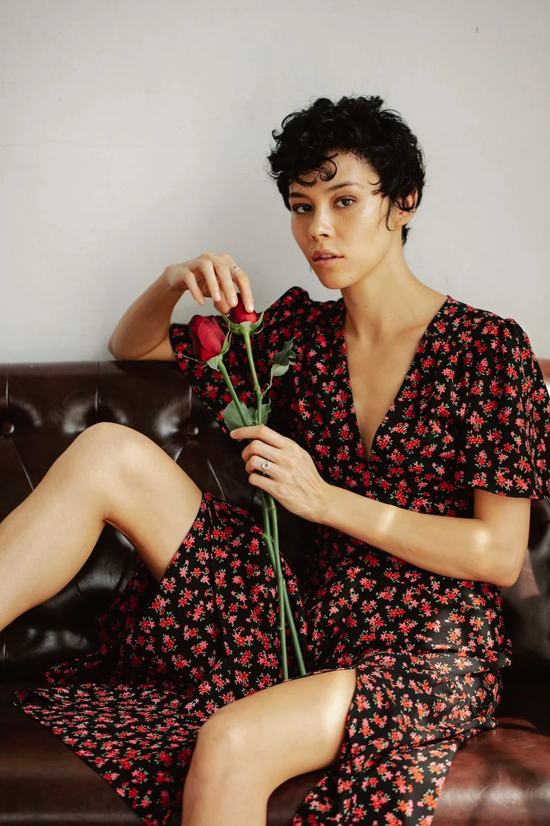 beautiful woman in a printed dress with a rose in her hand