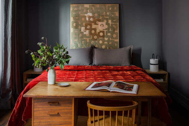 red velvet bedding, dark walls, desk at end of bed, unique side table lamps