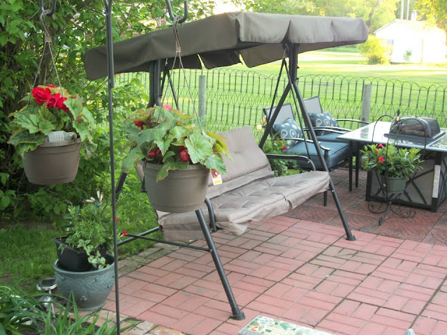 swing and hanging  flowers by swing on brick patio