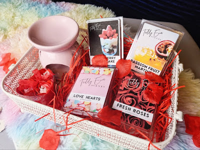 Photograph of the wax melt clamshells in a storage crate with a wax melt burner