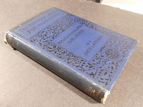 Image of cover and spine of A New England Girlhood as described in the text. The cover is dark blue with black lettering and floral design on front cover. The spine is stamped with gold lettering.