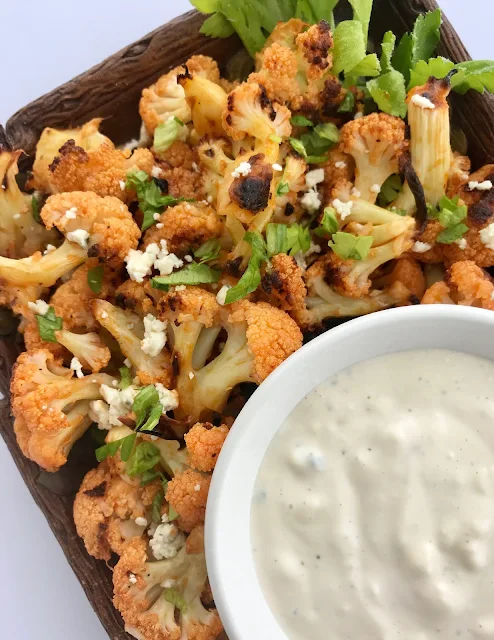 Finished platter of roasted Buffalo cauliflower with a bowl of blue cheese dressing.