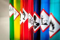 The image shows a row of bottles with warning signs on them.