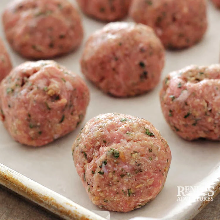 Raw air fryer turkey meatballs shaped into balls and sitting on a parchment lined baking sheet
