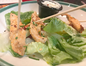 nashville chicken skewers on bed lettuce with pot sauce on side 