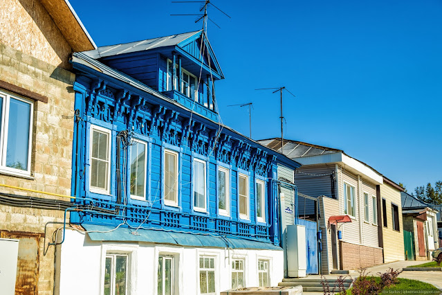 Двухэтажный синий деревянный дом с обилием резьбы