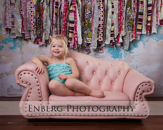 Girl in blue romper on a pink couch
