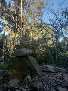 Steinpyramide vor Palmen und unter blauem Winterhimmel