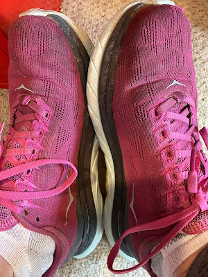 Photo of my feet wearing beat-up bright pink Hokas.