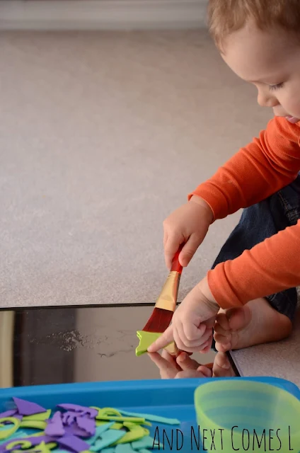 Toddler painting with water on a mirror