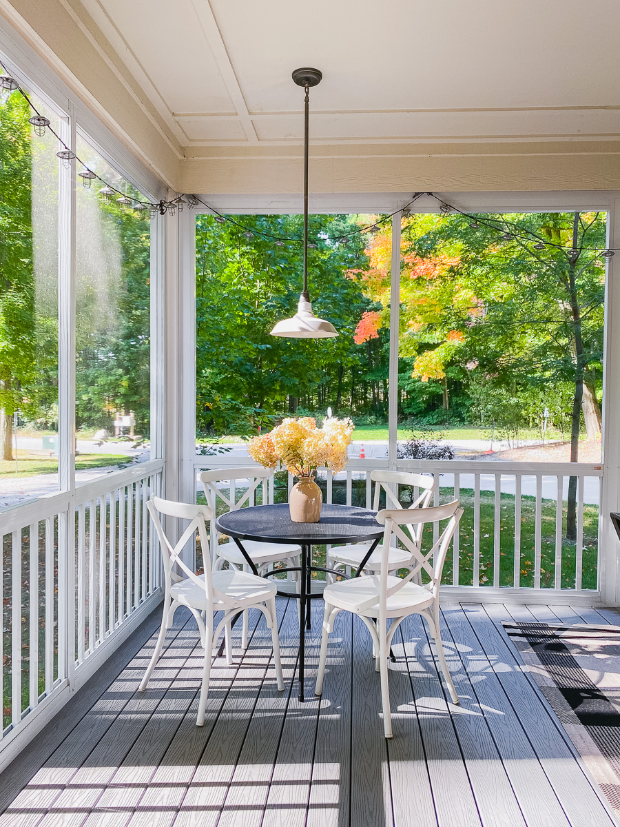 screened in porch with round dining table and pendant light